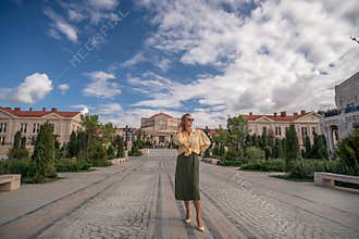 Woman, City, Street: Tourist posing in front of an ornate building in a European city on a sunny day.