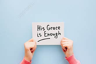 His grace is enough - woman hands with christian motivational text on light blue background