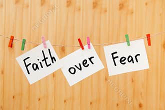 Faith over fear - christian lettering on wooden background, card with text on rope and colorful clothespin