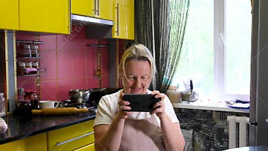 Take away the mobile phone from the husband adult woman housewife apron home conditions wife hits husband with towel