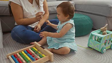 Woman playing with toddler daughter in living room with abacus toy