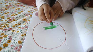 A child is engaged in the creative activity of making art using a crayon on paper