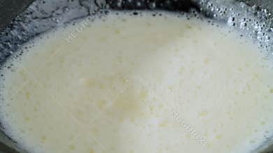 A beaten egg with milk is slowly stirred in a black bowl. Preparation of sweet food. Slow motion 4k footage.