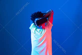 African sport player wearing VR stretching arm neon light wall. Contrivance.