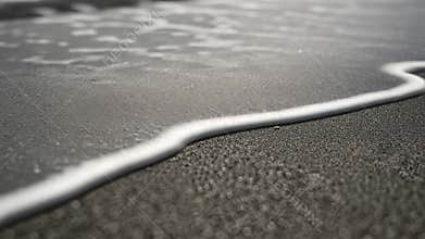 Discover the intricate sand beach texture as waves gently flow and recede in natural patterns