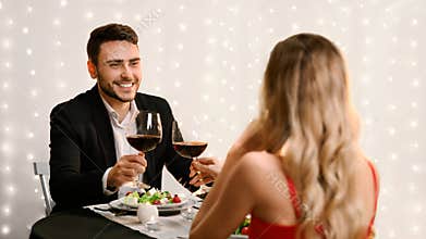 Romantic couple clinking wine glasses during Valentine Day dinner in restaurant