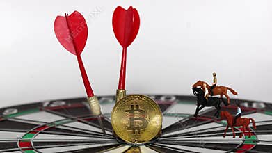 Two arrowheads and Bitcoin on a dart board with three miniature men riding horses.