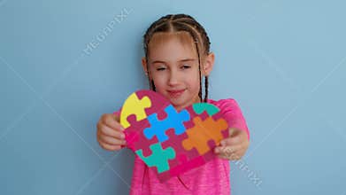 A child with an autism symbol in his hands on a blue studio background.