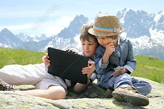 Two boys with tablet PC in mountains