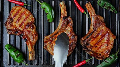 Lamb chops pork with bone on grill. Turn meat. Top view. Slow motion. Loin on ribs