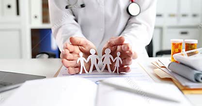 Doctor hugging paper figures of family bangs with his hands 4k movie slow motion