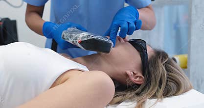 The doctor eliminates defect on a woman's chin with a laser