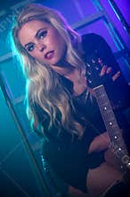 Woman holding electric guitar in a backstage