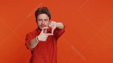 Man photographer gesturing picture frame with hands, looks through fingers focusing cropping image