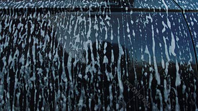 Dirty foam after washing a car flows onto the grass and soil. Pollution of nature and the environment, ecology. Slow