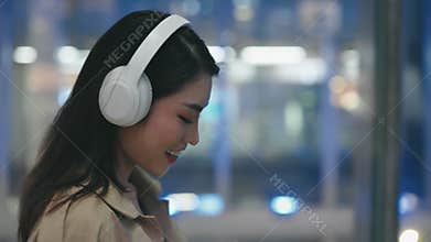 Charming Young Girl in White Headphones Walking Outside and Enjoying Music.