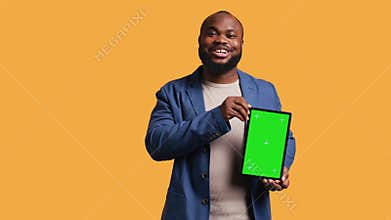 Amused man laughing while presenting tablet with green screen display