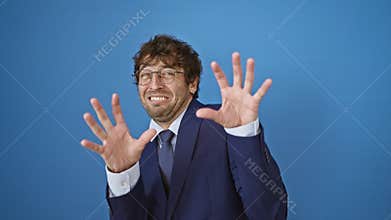 Terrified young man in business suit shouting in fear, hands displaying a stop gesture, consumed by panic. frustrated expression
