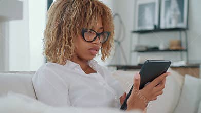 Woman sitting on couch using tablet