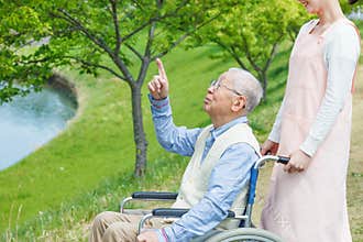 Asian senior man sitting on a wheelchair pointing