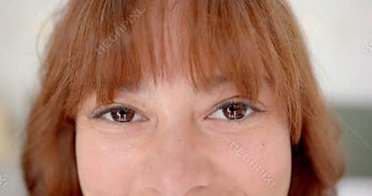 Close-up of a young biracial woman with brown eyes and bangs