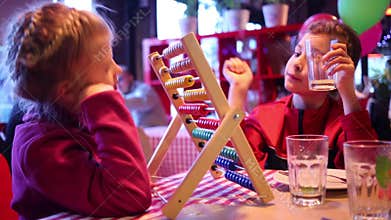 Two little girls play with abacus in cafe with