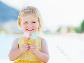 Smiling baby eating two ice cream horns