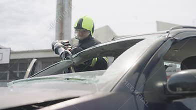 A courageous firefighter, equipped with specialized tools, heroically rescues people trapped in a car accident