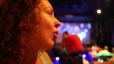 Woman singing into a microphone at a karaoke club