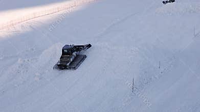 Snow groomers assemble heap of snow on slope of
