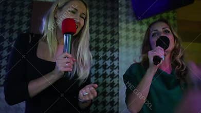Two joyful women singing and dancing in karaoke