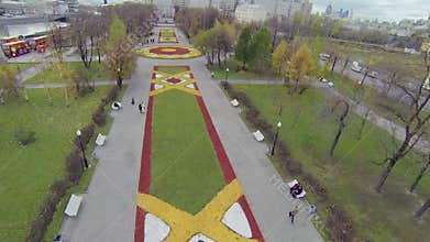People walk near colorful flowerbeds in park of