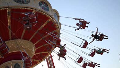 Many people ride on carousel. Under view with blue