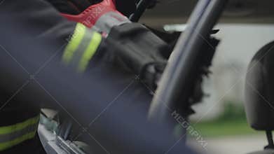 A courageous firefighter, equipped with specialized tools, heroically rescues people trapped in a car accident