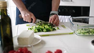 Woman At Home In Kitchen Cutting Cucumbers