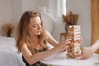 two women playing Jenga board game at home, excitement and relaxation, mind development concept,