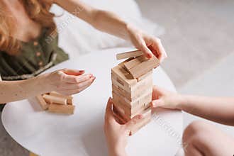 two women playing Jenga board game at home, excitement and relaxation, mind development concept,