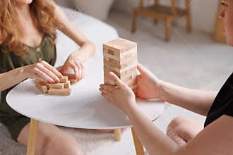 two women playing Jenga board game at home, excitement and relaxation, mind development concept,