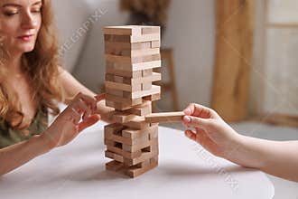 two women playing Jenga board game at home, excitement and relaxation, mind development concept,