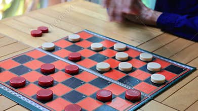 Senior asian father and son are enjoy playing checkers board game at home for leisure activities hobby and preventing from alzheim