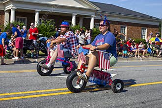 Two people having fun riding tricycles in the Fourth of July parade