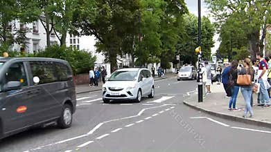 Tourists posing on Abbey Road zebra crossing made famous by the Beatles album cover \"Abbey Road\" in 1969