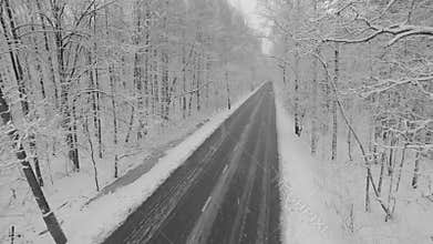Car ride away by road during snowfall in