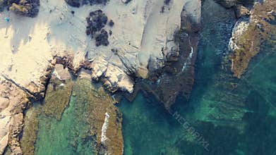 Aerial view of a rocky shoreline next to a calm water body