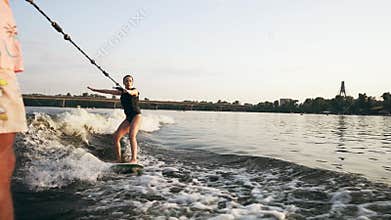 A young woman is wakeboarding.