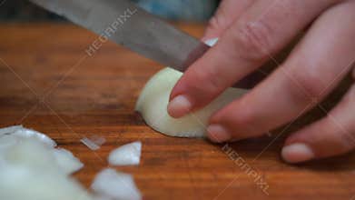 Slicing vegetables onion. A Woman Chef cutting onion with knife while cooking while making homemade dish Close-up.
