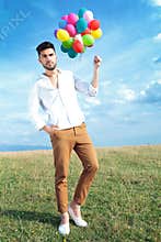 Casual man with balloons and hand in pocket