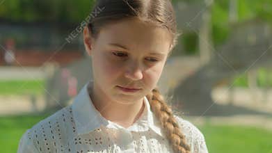 Sad alone pensive serious little girl child Caucasian adopted kid female orphan schoolgirl student in city look down