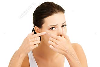 Young woman with pimple on her face. Trying to squeeze it.