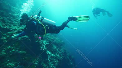 Divers with oxygen tanks explore underwater nature